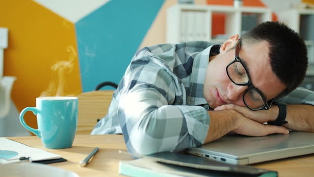 man sleeping at desk with coffee nearby Photo by Vitaly Gariev on Unsplash sleepy